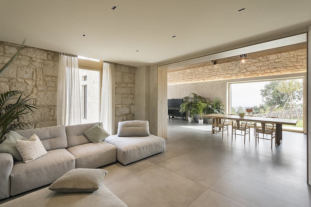 A spacious, contemporary living room with stone walls, large windows, and an open floor plan.