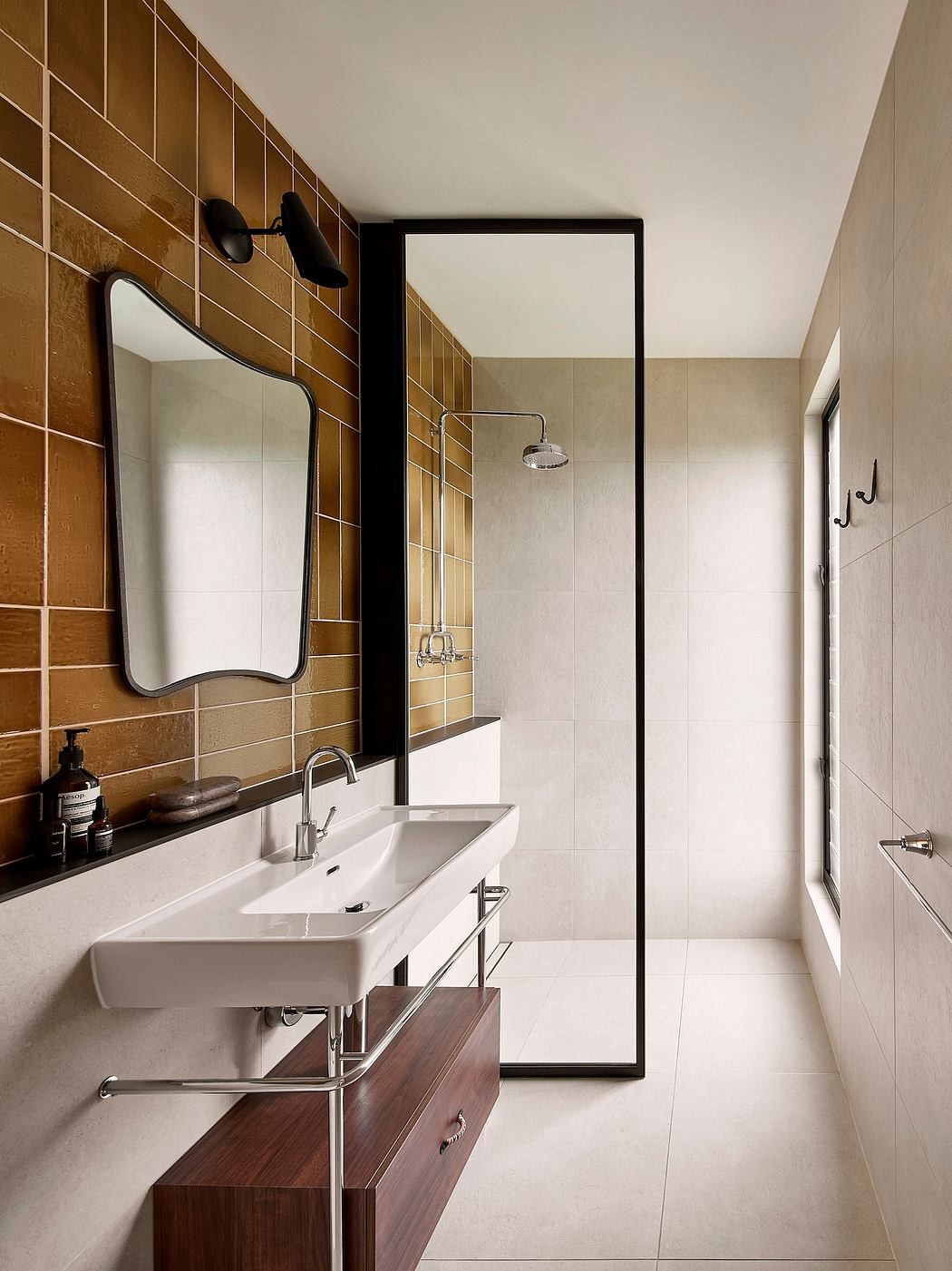 A modern bathroom with a large wall-mounted mirror, wooden vanity, and sleek shower fixture.