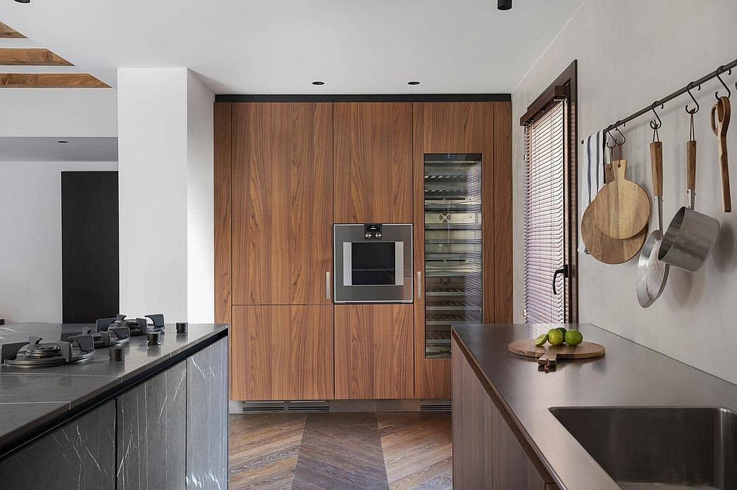 Sleek modern kitchen with wood paneled walls, stainless steel appliances, and hanging cooking utensils.