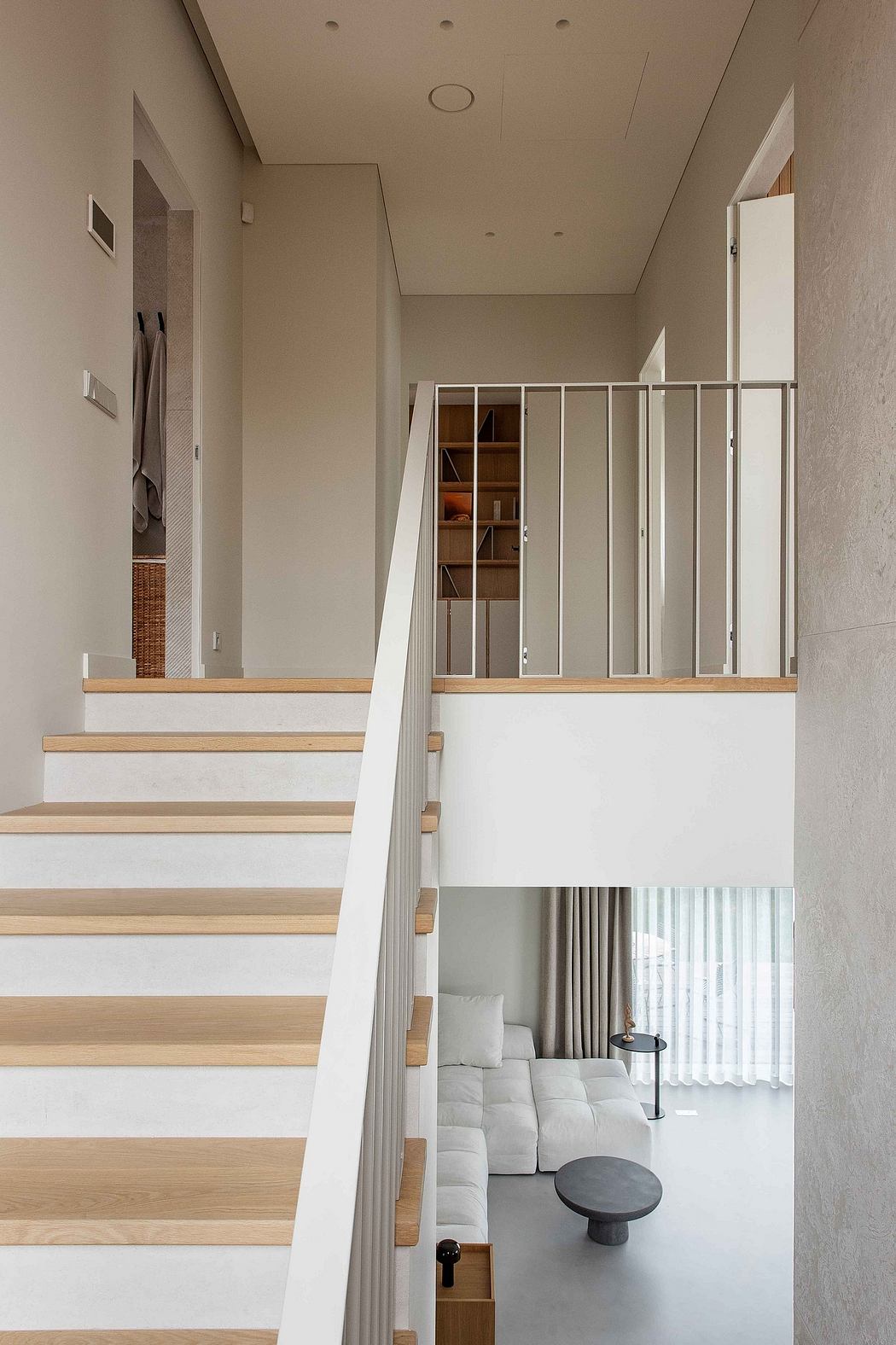 Minimalist staircase with wooden steps and metal railings, leading to a cozy living area.