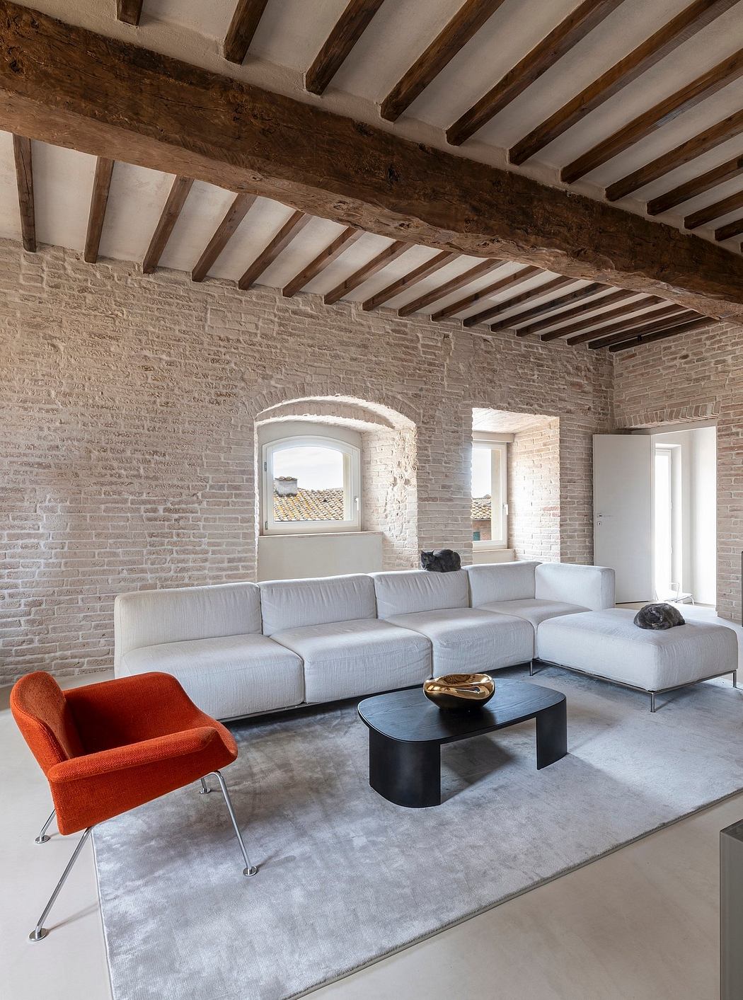 Rustic wooden beams, exposed brick walls, and a modern modular sofa create a stylish interior.
