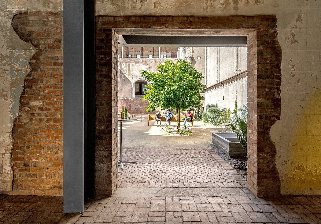Brick archway frames a courtyard with trees, benches, and paved walkway.