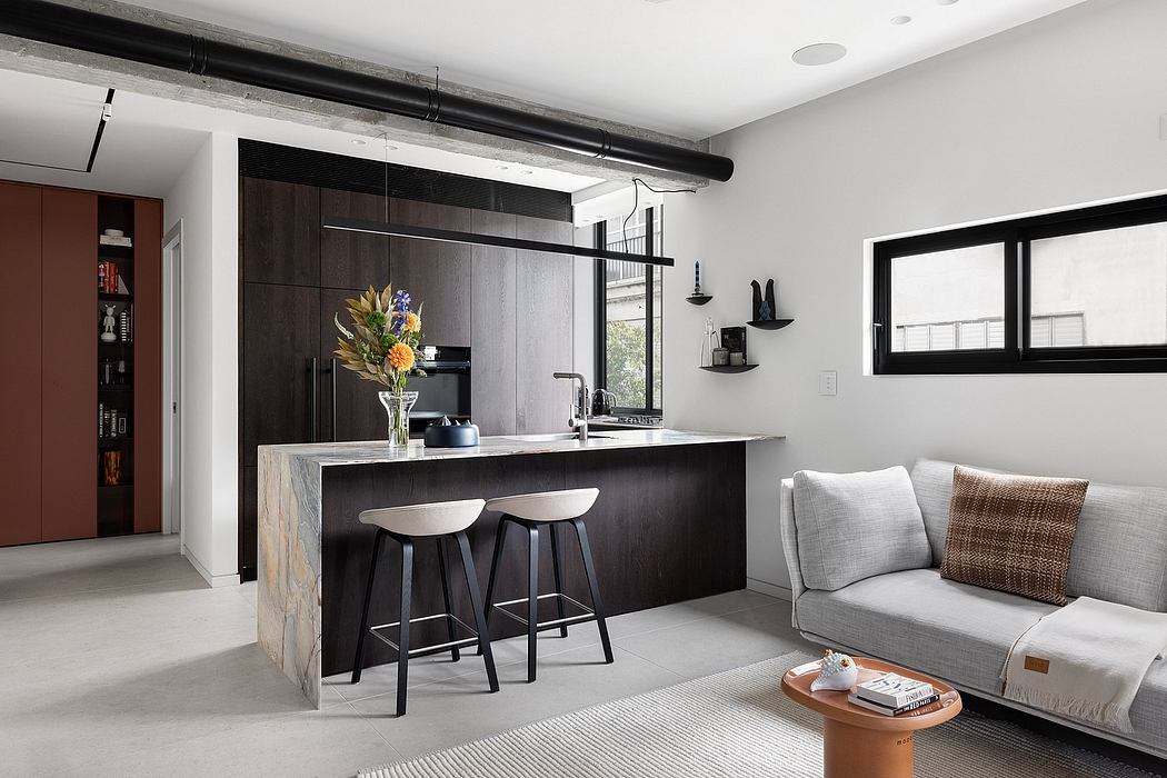 Modern open-concept kitchen with dark cabinetry, concrete countertop, and gray sofa.