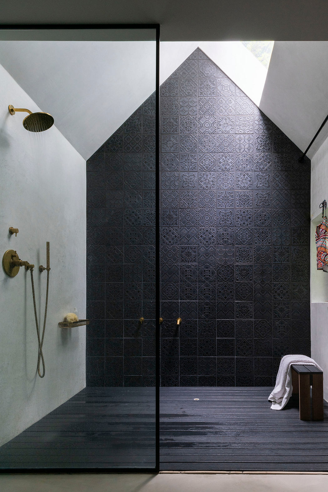 Dramatic black tiled wall with ornate patterns and geometric shapes in a minimalist bathroom.