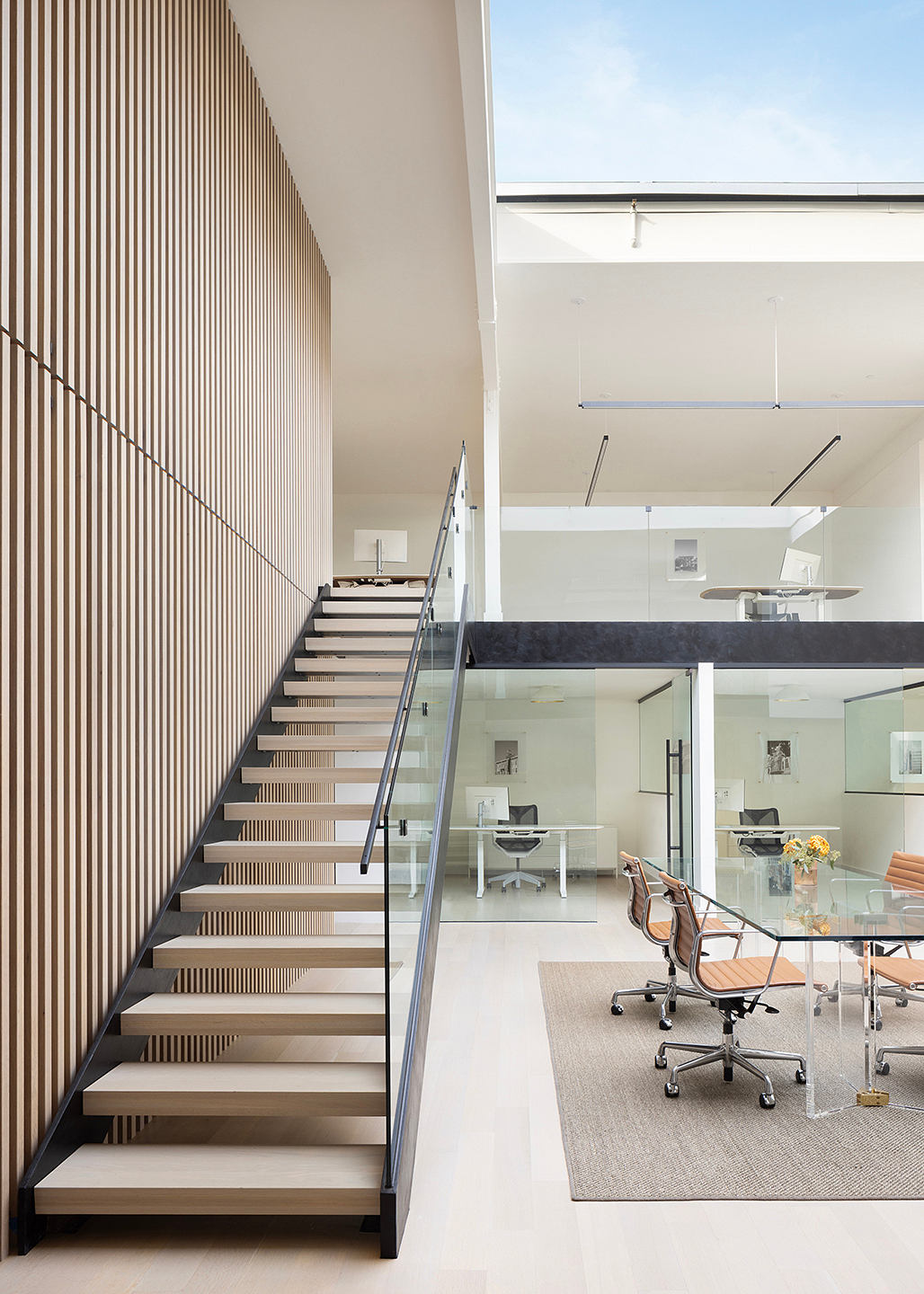 A modern, geometric staircase leads to an open-concept office space with sleek furnishings.