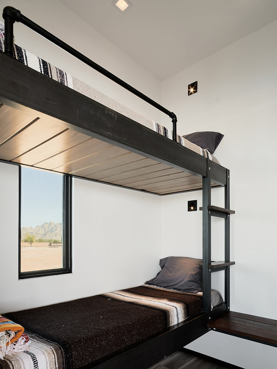 A modern, minimalist bunk bed setup with a large window overlooking a scenic landscape.