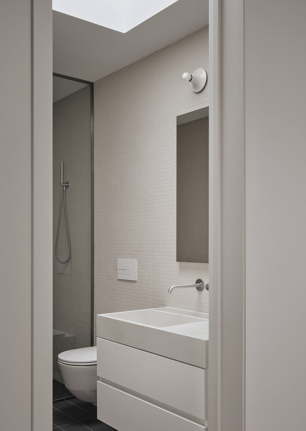 A minimalist bathroom with white tiles, a sleek vanity, and recessed lighting.