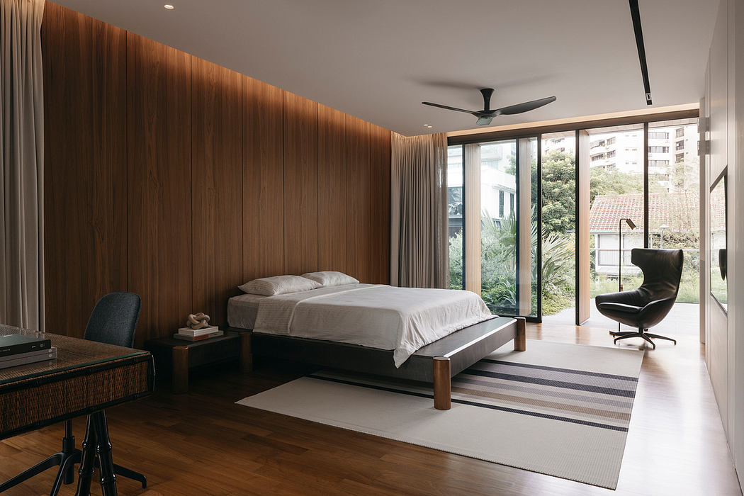Spacious bedroom with warm wooden walls, large windows, and modern furnishings.