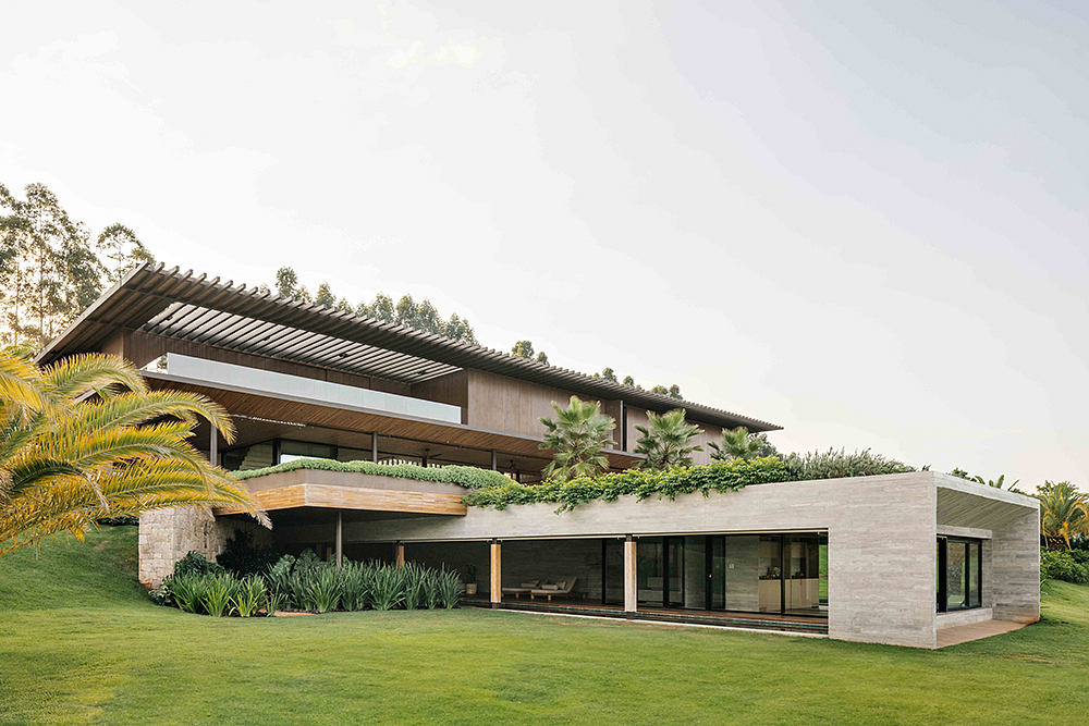 Striking modern architecture with expansive glass walls, wooden beams, and lush landscaping.