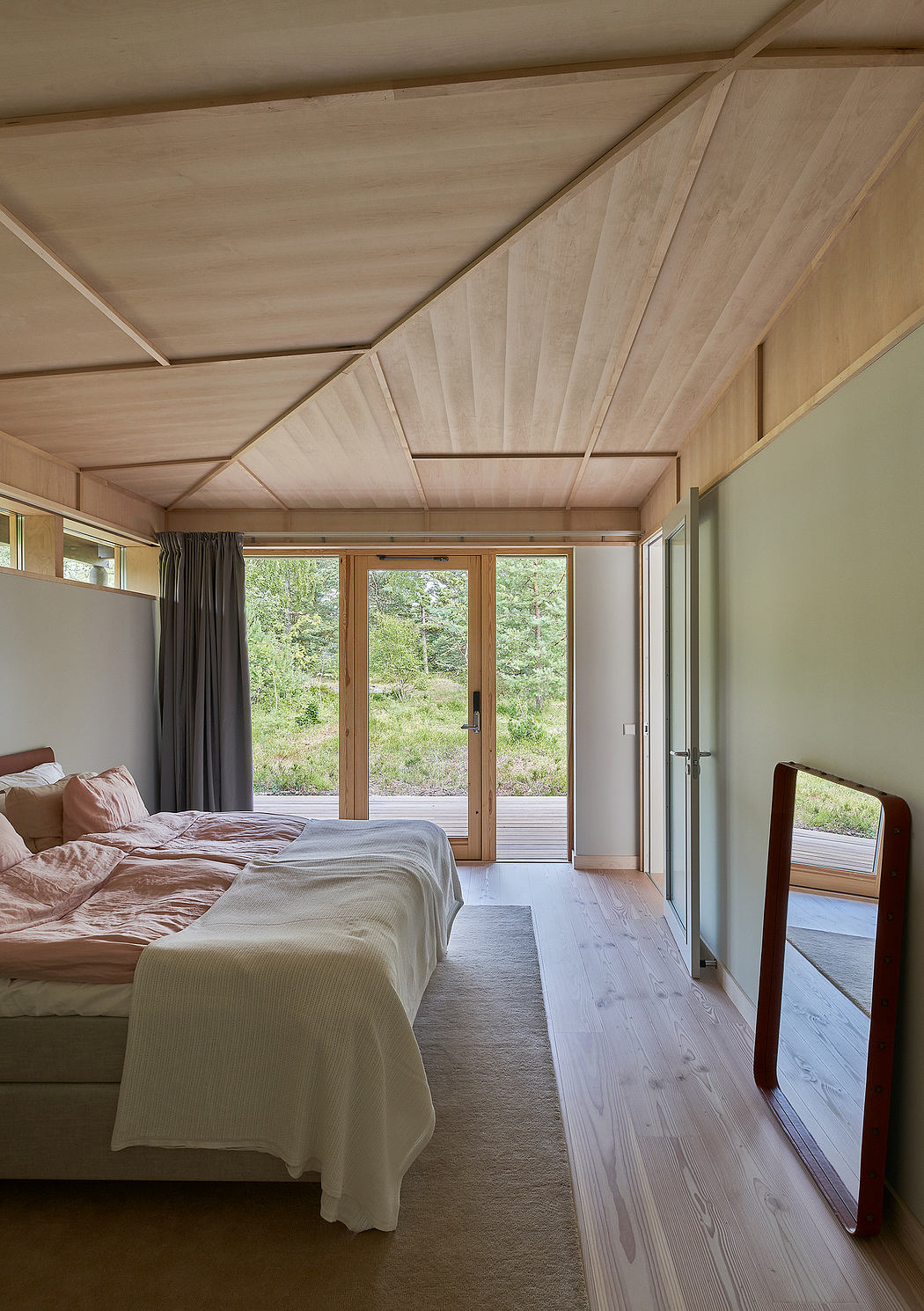 Cozy wooden cabin interior with vaulted ceiling, large windows, and neutral decor.