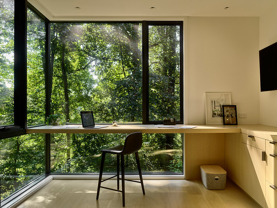 Well-lit modern home office with expansive windows overlooking lush greenery.