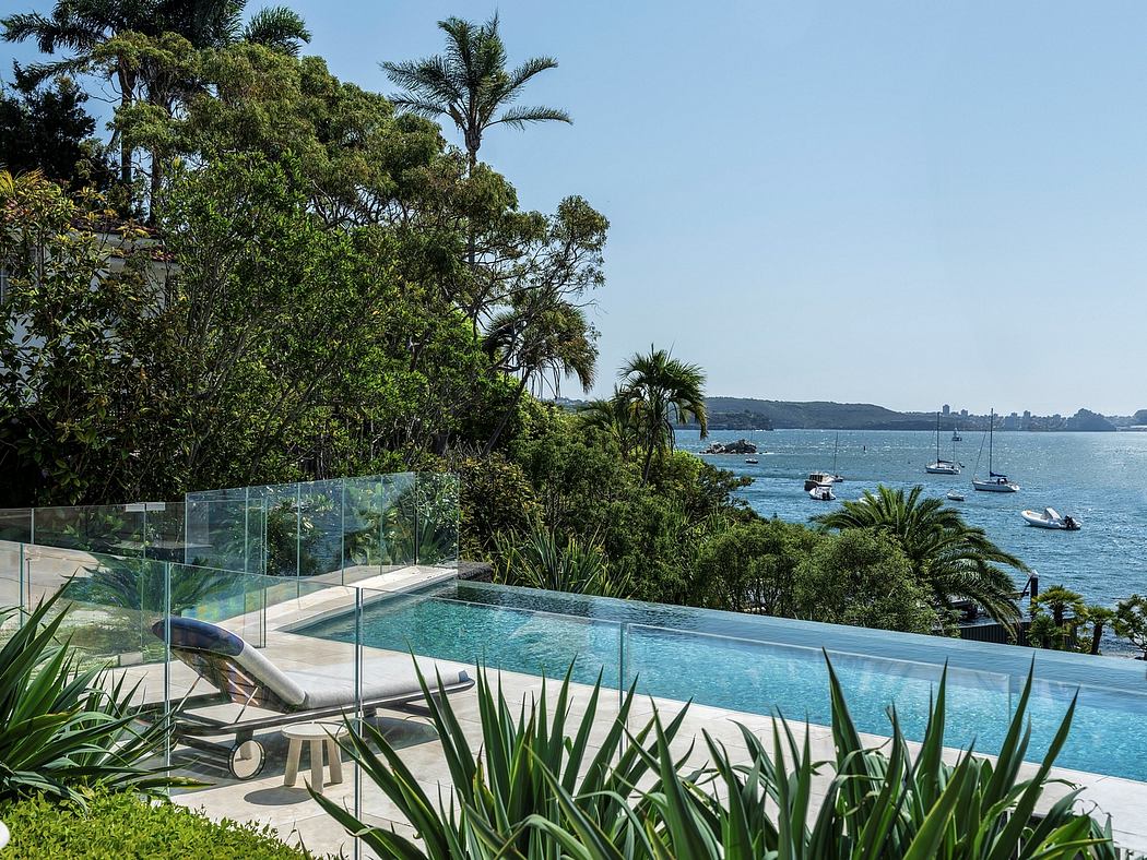 A modern, glass-enclosed pool overlooking a lush, tropical landscape and the ocean.