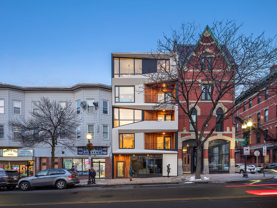 Striking modern apartment building with glass facades and brick accents, framed by bare trees.