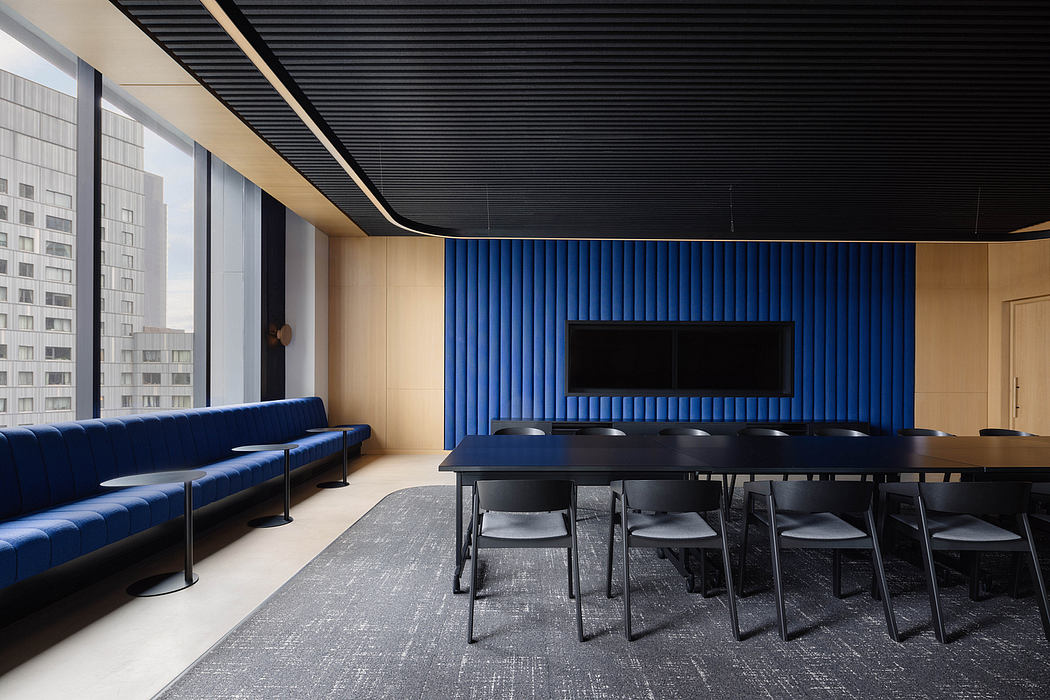 Modern office space with sleek blue paneled walls, black table, and plush navy sofa.