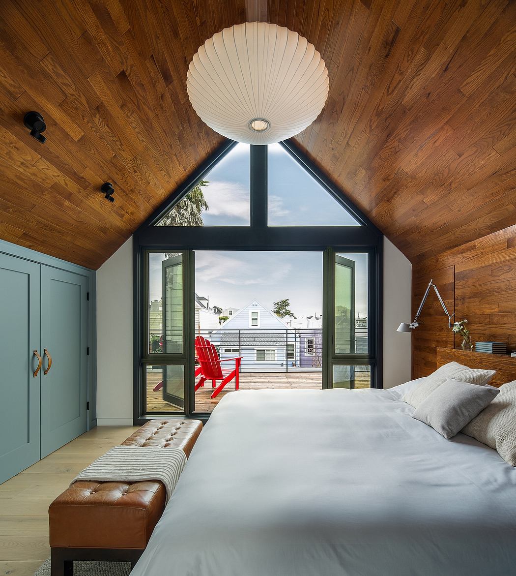 A cozy bedroom with a large triangular window offering a scenic view, complemented by warm wood paneling.