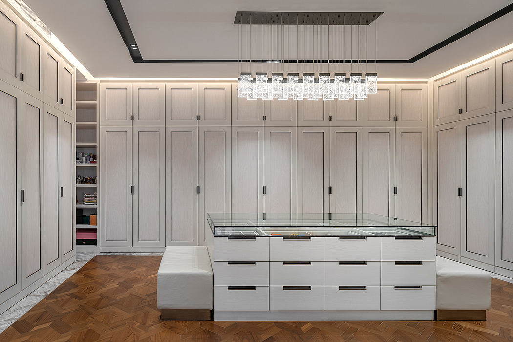 Expansive, minimalist closet space with sleek cabinetry and modern lighting fixture.