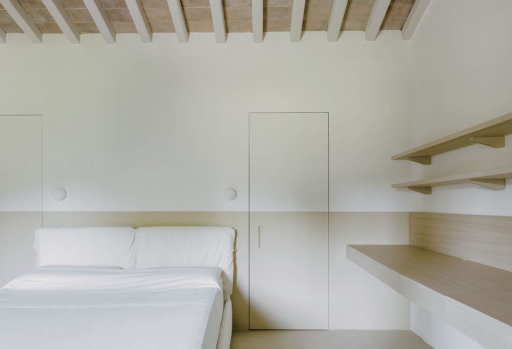Minimalist bedroom with wooden beam ceiling, built-in shelving, and white bedding.