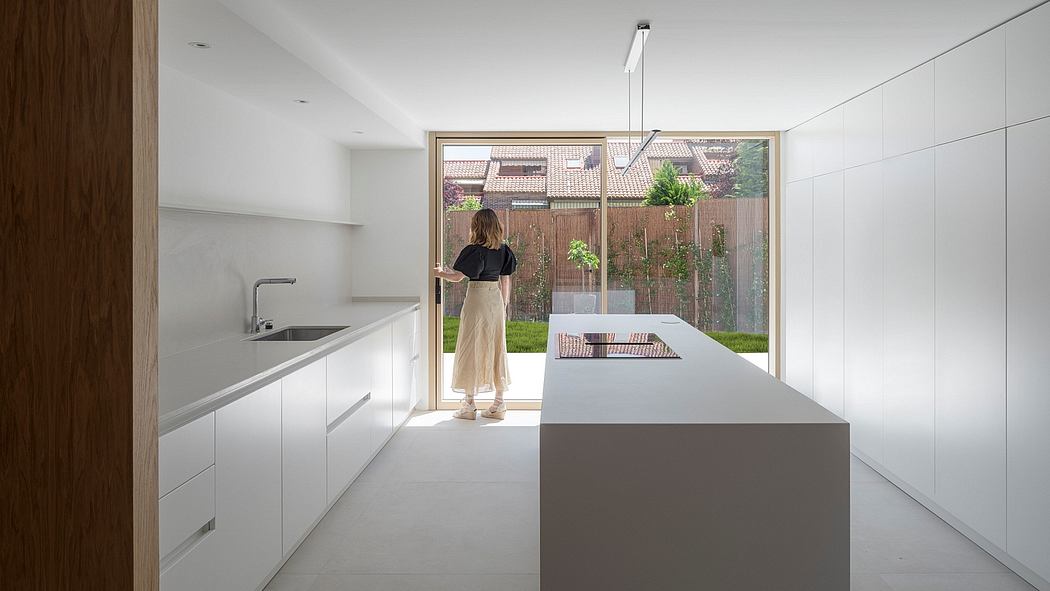 A modern, minimalist kitchen with a large glass window overlooking the backyard.