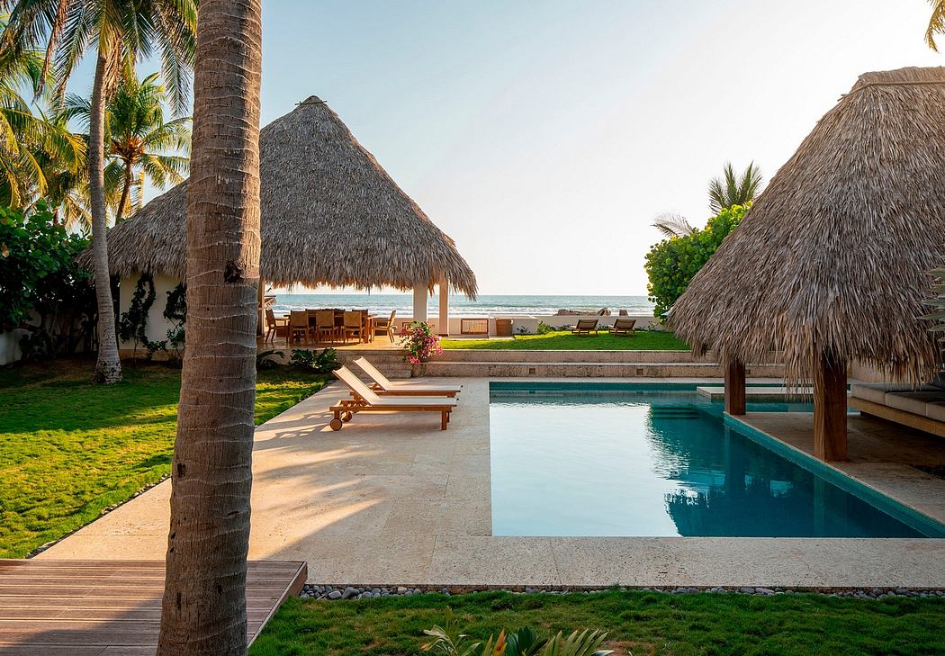 Tropical resort with thatched roof cabanas, palm trees, and infinity pool overlooking the ocean.