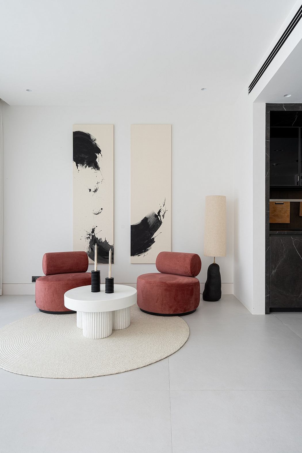 Minimalist living room with abstract art, curved pink chairs, and a white round coffee table.