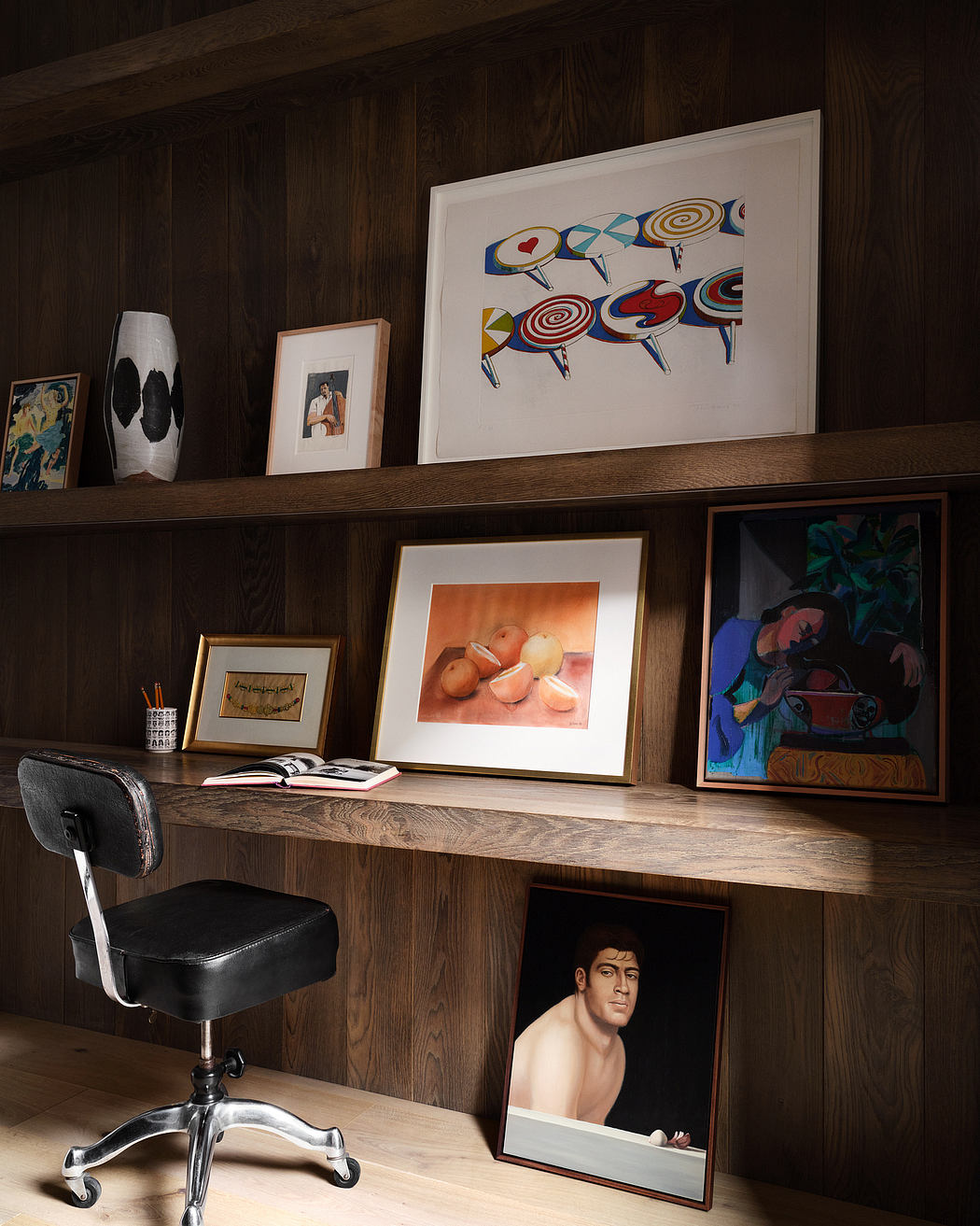Cozy home office with wooden shelves displaying diverse artwork and decor.