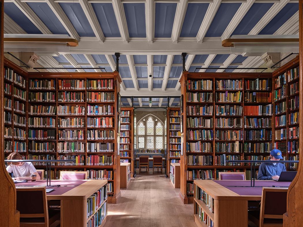 A grand library with towering bookshelves, Gothic-style arched windows, and a vaulted ceiling.