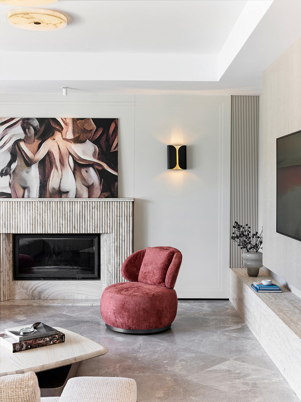 Cozy living space with modern fireplace, plush red chair, and abstract artwork.