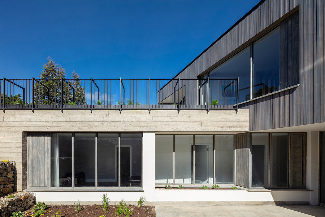Sleek, modern exterior with concrete walls, large glass windows, and a metal railing balcony.
