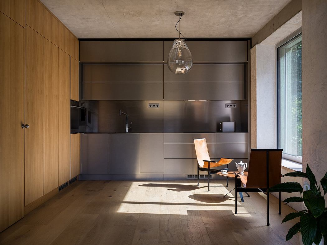 This modern kitchen features sleek, dark cabinetry, a large window, and a pendant light fixture.