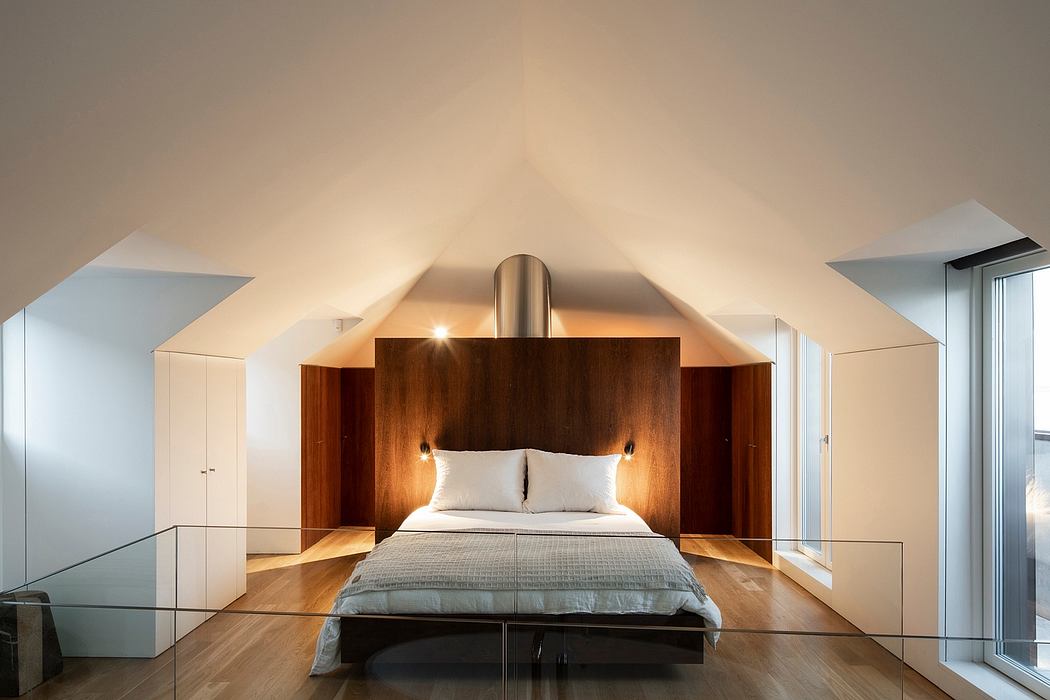 Cozy attic bedroom with wooden paneled walls and a modern stainless steel light fixture.