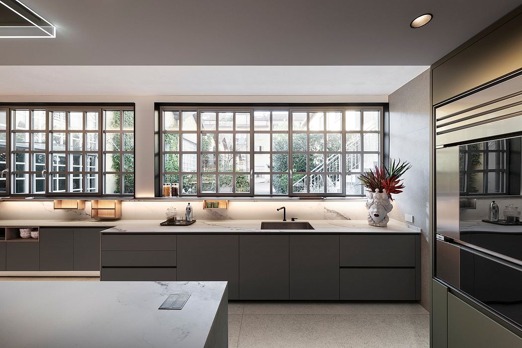 Modern kitchen with sleek black cabinetry, large windows, and marble countertops.