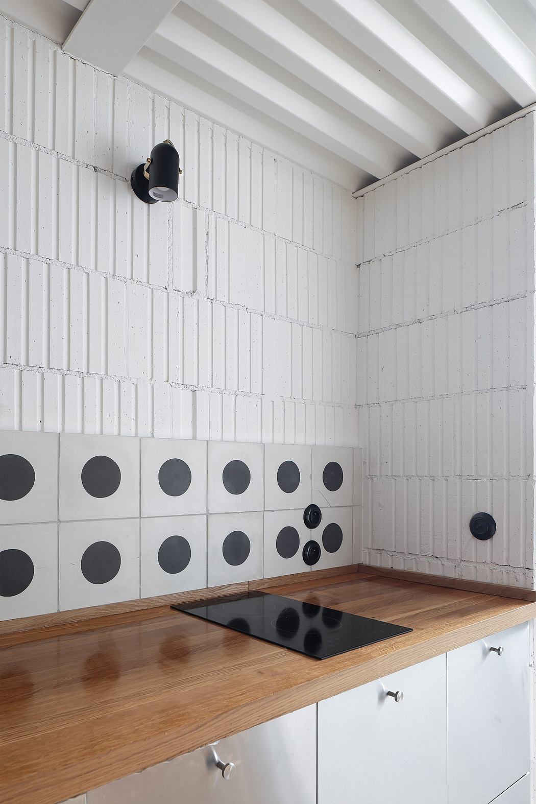A modern, minimalist kitchen with white walls, wood countertops, and circular black accents.