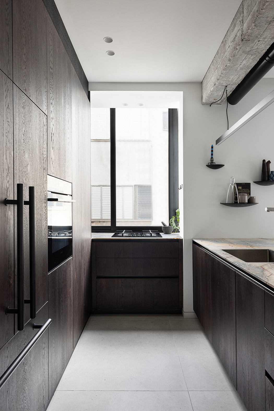 A contemporary kitchen with sleek, dark wood cabinetry, recessed lighting, and minimalist shelves.