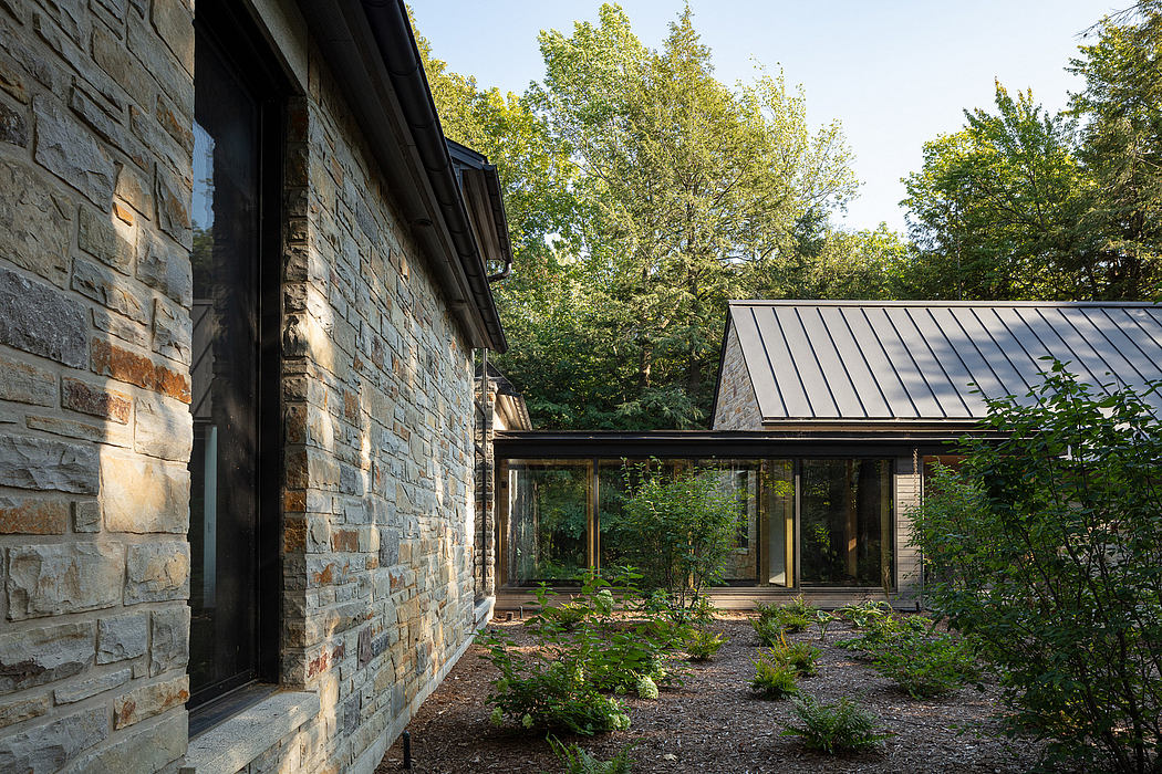 A modern stone-and-glass building nestled in a lush, forested environment.