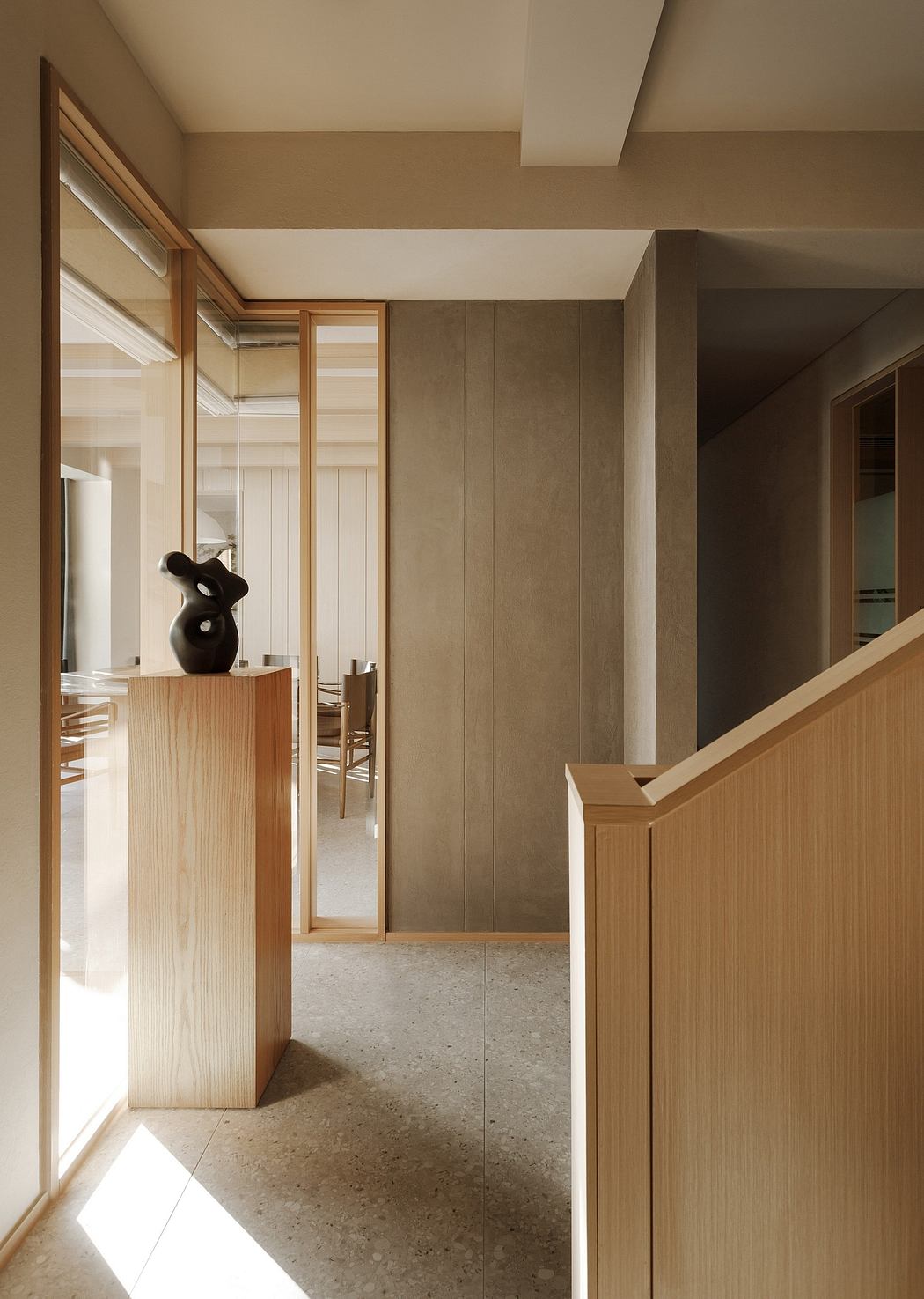 Minimalist hallway with wood paneling, abstract sculpture, and tiled floor.