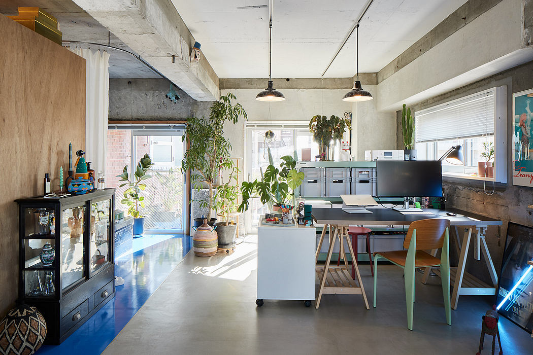 Spacious, modern loft-style workspace with concrete walls, hanging plants, and industrial lighting.