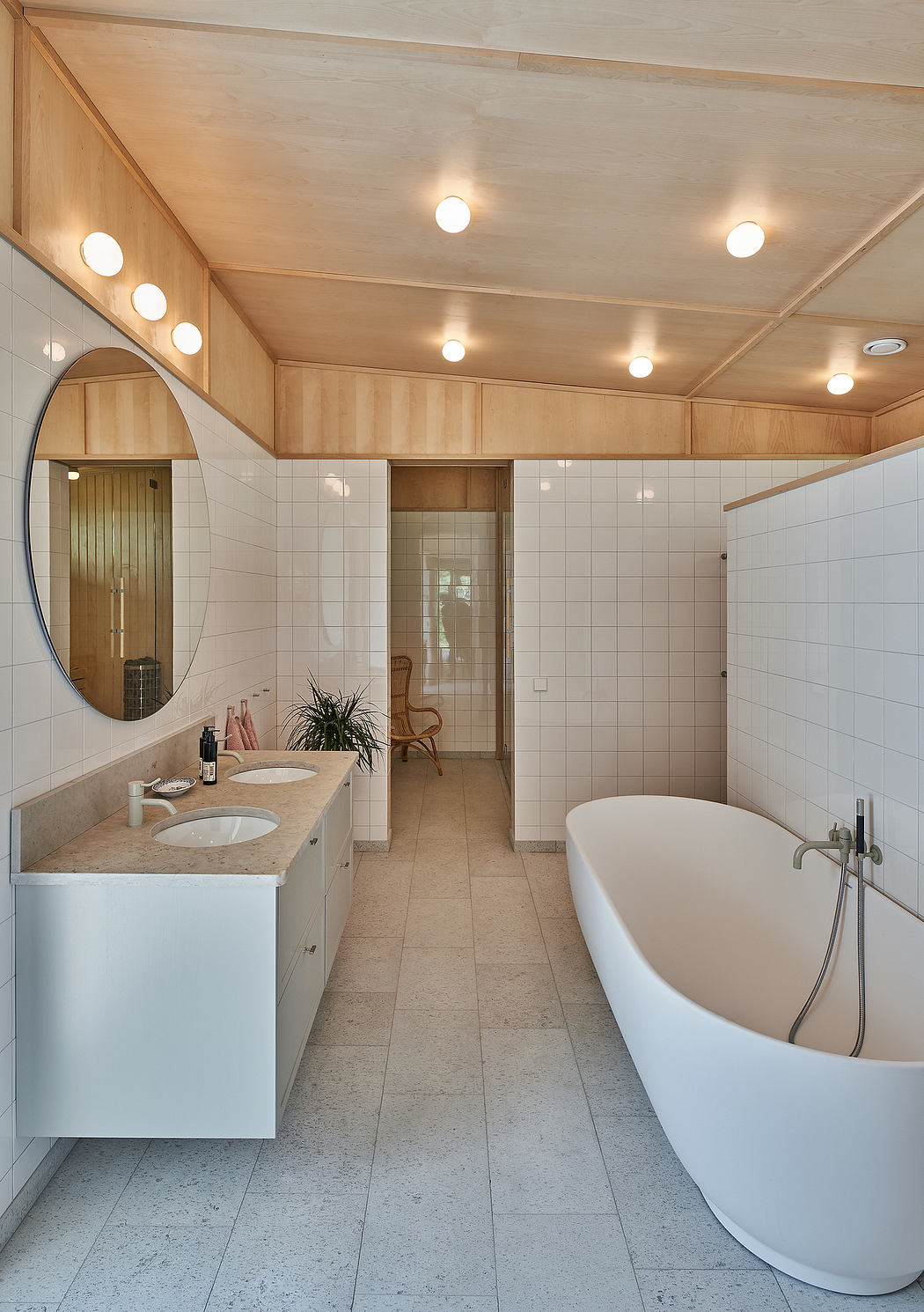 Bright, spacious bathroom with wooden paneling, oval mirror, and standalone tub.
