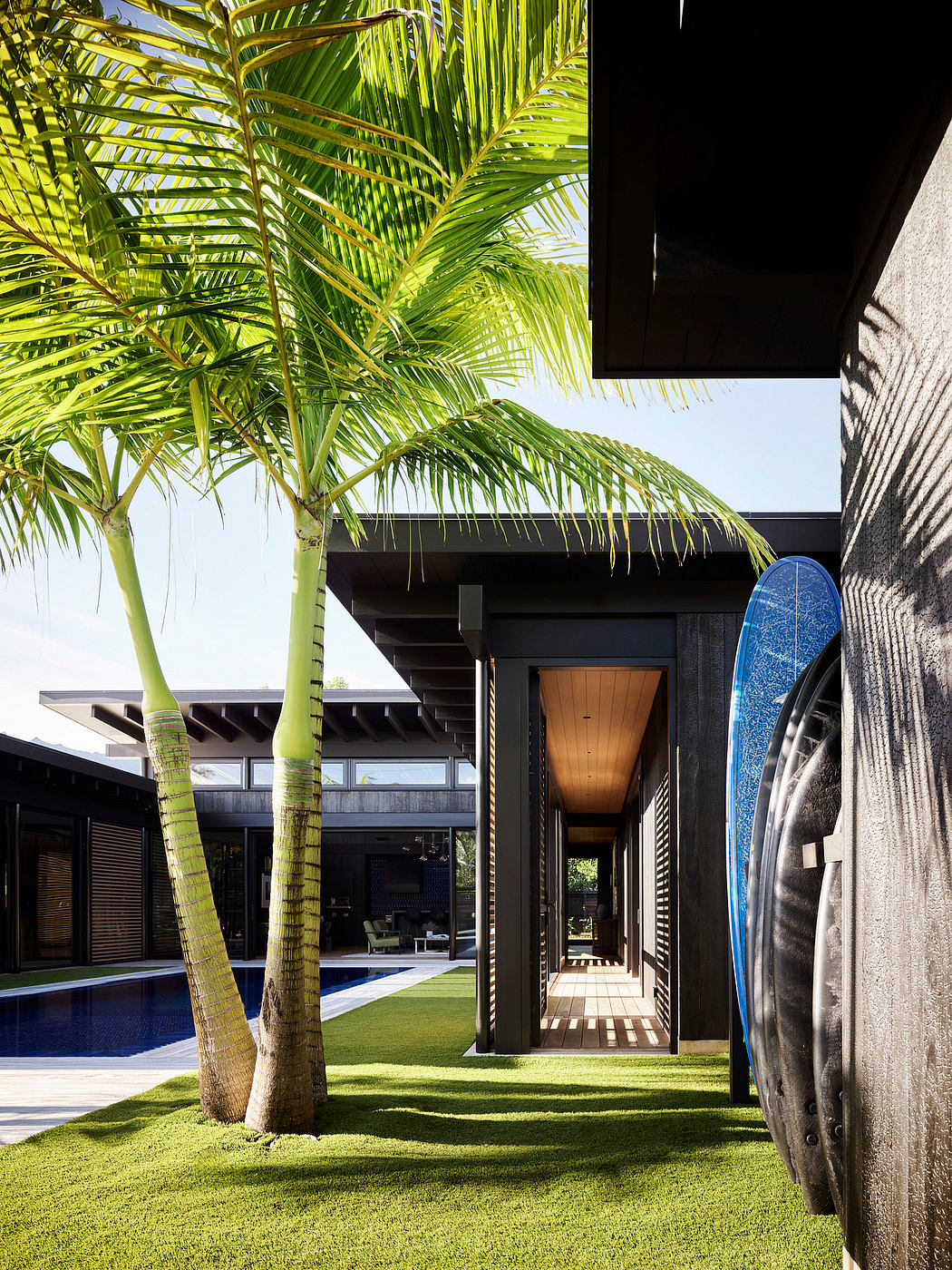 Lush tropical grounds surround a modern, minimalist building with an inviting entryway.