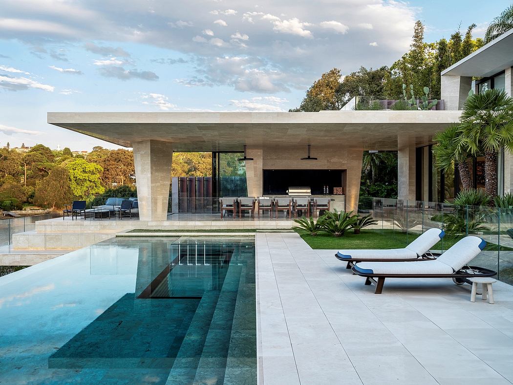 Sleek modern home with expansive outdoor living area, infinity pool, and lounge chairs.