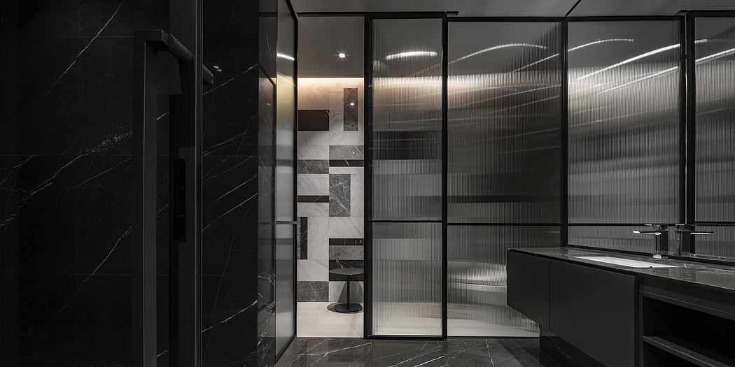 Modern, sleek bathroom with black and white tiled walls, glass dividers, and recessed lighting.