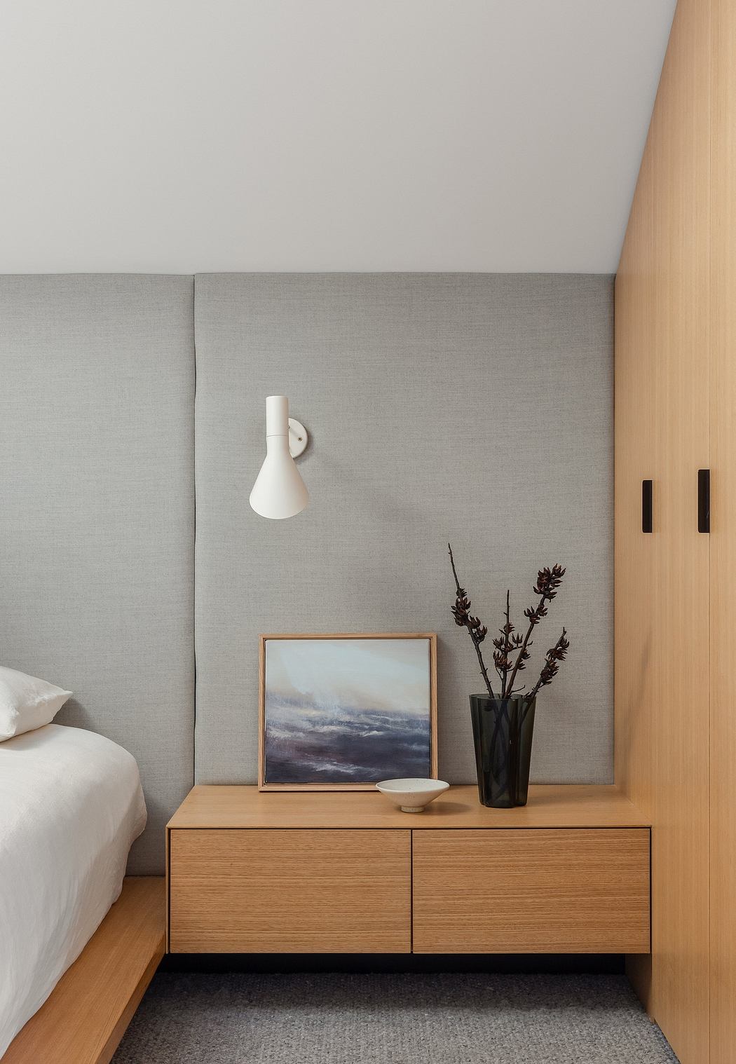 Minimalist bedroom with wood furniture, framed artwork, and simple decor accents.