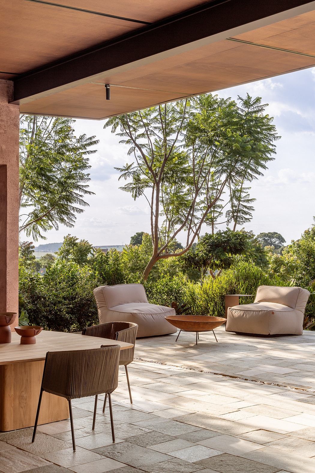 Cozy outdoor lounge area with modern furniture, stone tiling, and lush tropical foliage.