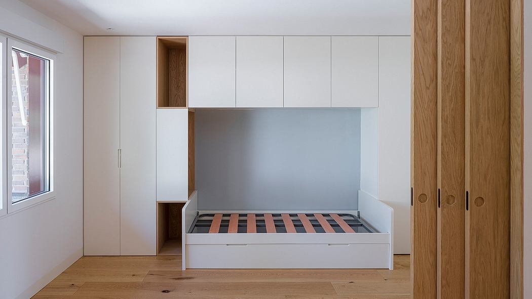 A spacious, minimalist bedroom with built-in cabinetry, wooden floors, and a modern bed frame.
