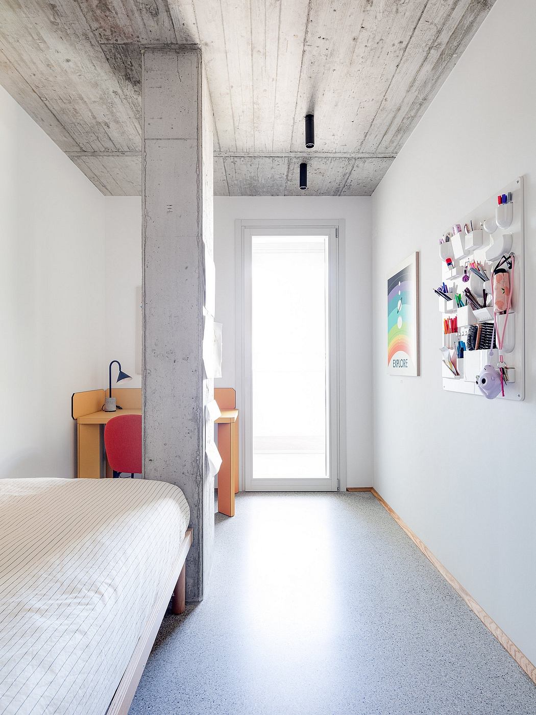 Minimal, modern bedroom with concrete ceiling, bright window, and organized shelving.