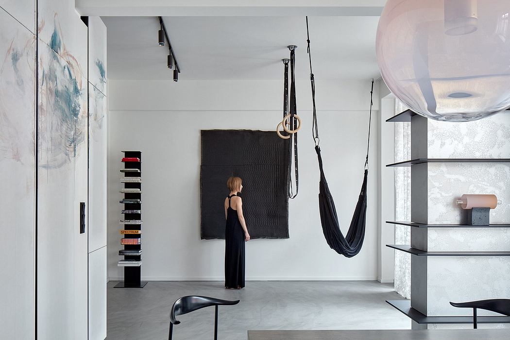Modern minimalist interior with sleek black accents, suspended aerial yoga equipment, and built-in shelving.