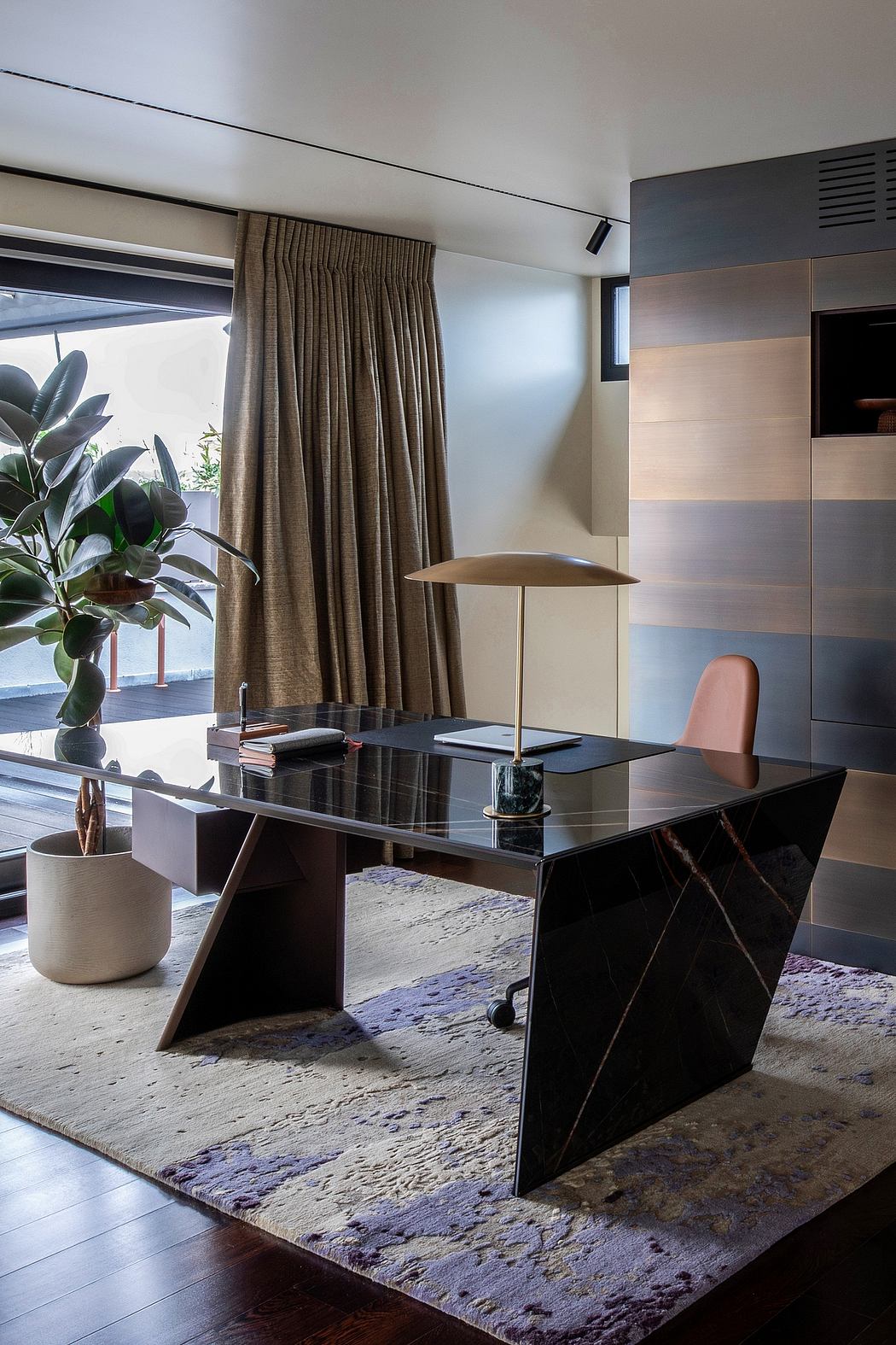 Modern office space with sleek black desk, pink chair, and lush indoor plant.