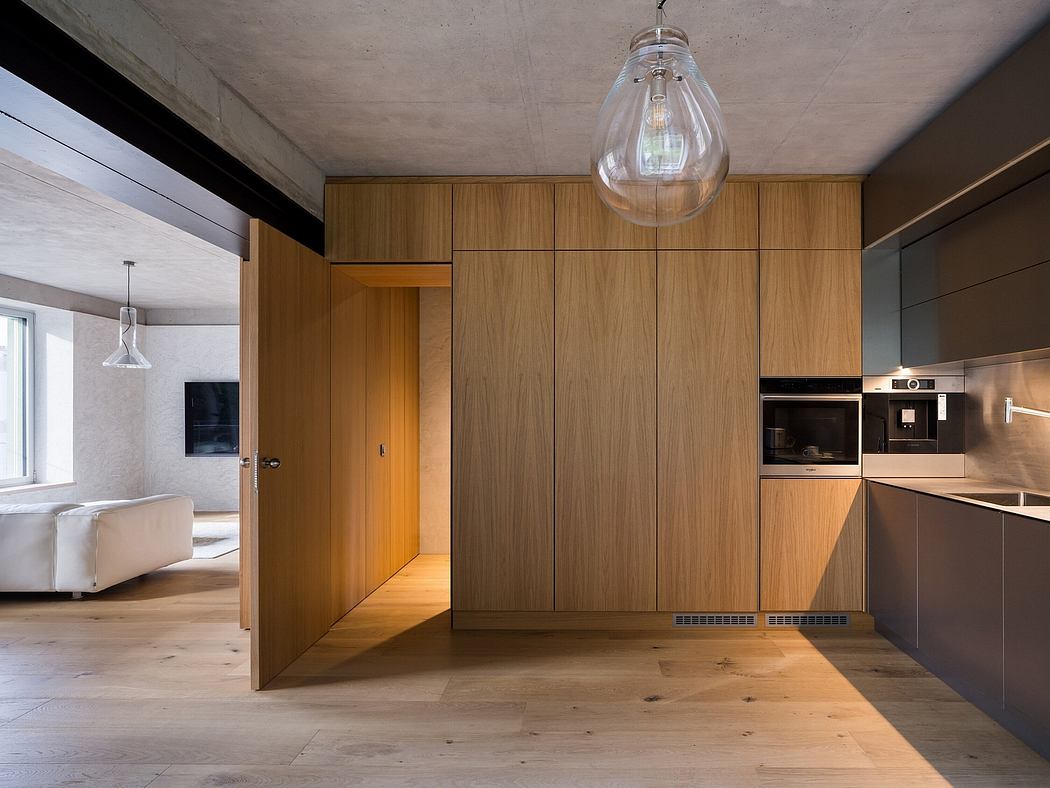 Sleek, minimalist kitchen design with wood paneling, glass pendant light, and built-in appliances.