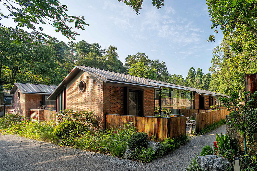 A modern, brick building with a wooden deck and glass walls surrounded by lush greenery.