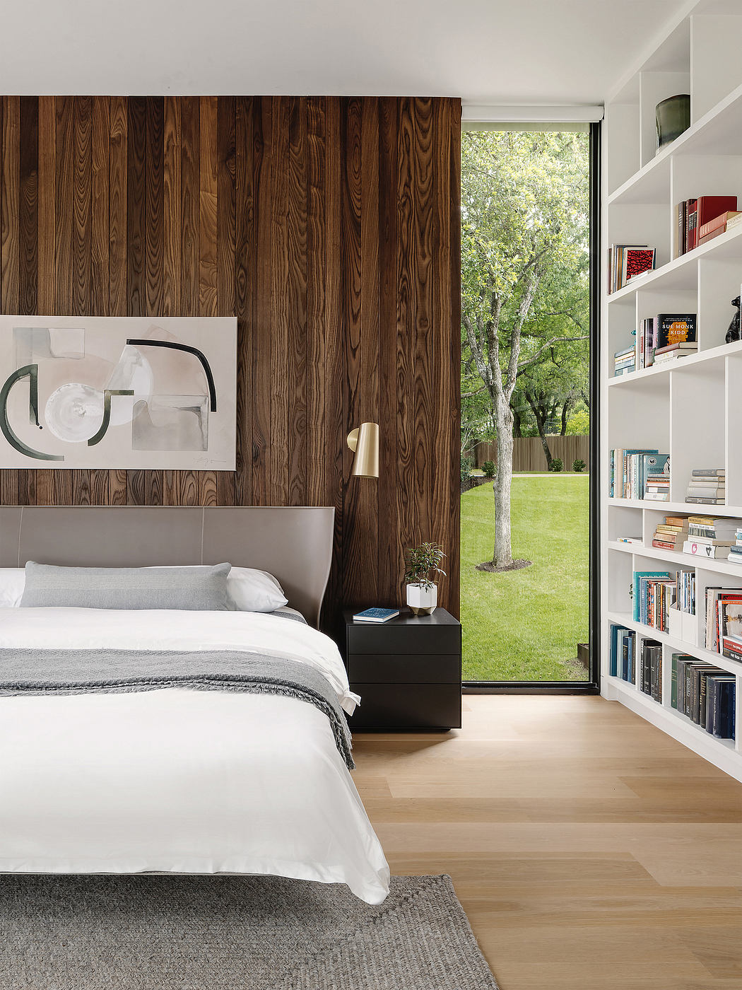 Spacious bedroom with wooden accent wall, built-in shelving, and expansive views.