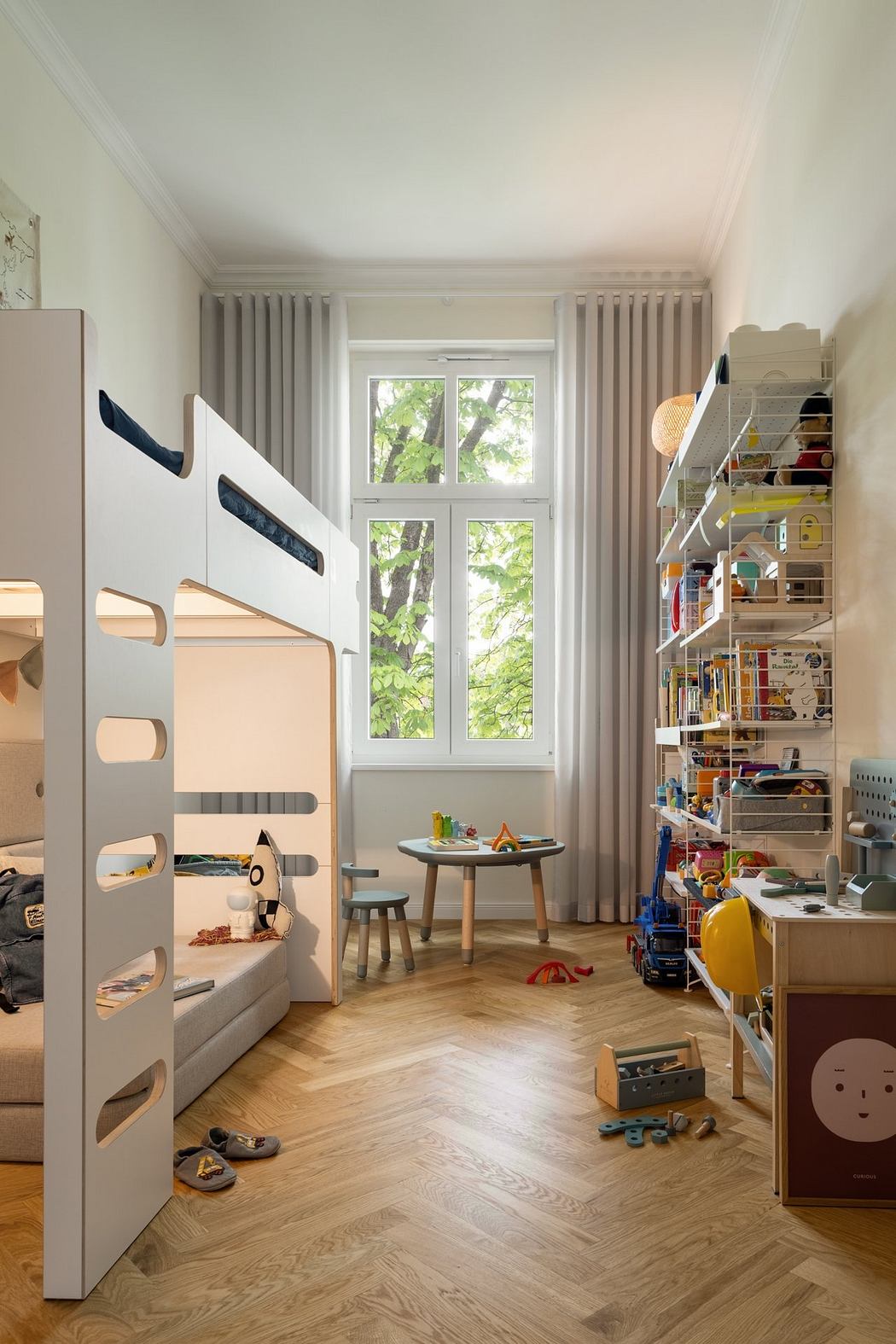 A cozy children's room with a bunk bed, curtains, and a well-organized shelf display.